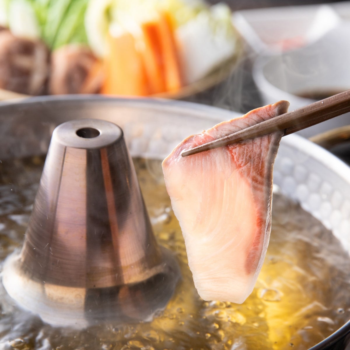 大分県産ブランド魚「かぼすぶり」の切り身を鍋でしゃぶしゃぶしている画像。