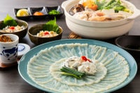 大分県産の高級魚「豊後とらふぐ」料理セットで楽しめる、てっさ（刺身）、てっちり（鍋）、ヒレ酒の豪華な食卓の盛り付け画像。ご贈答にも最適な大分のご当地ふぐセットを通販でお取り寄せ。