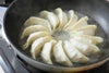 フライパンまたは鍋に「しそ餃子」を並べ、焼き色がついている調理中の画像。さわやかな大葉の香りが立ち上る、焼きの工程。
