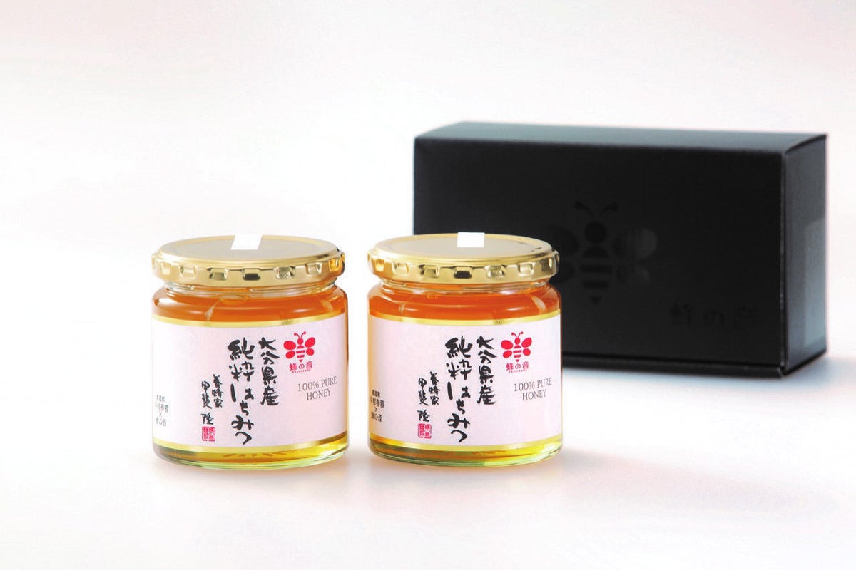 大分県で採蜜された「大分県百花はちみつ300g」の容器2本とギフトボックスを並べた画像。贈答やお返しに最適な、大分の四季の恵みを感じる純粋はちみつ。