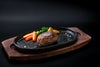 大分県のブランド牛「おおいた和牛（黒毛和牛）」を贅沢に使用したハンバーグの調理後の盛り付け画像。鉄板の上で肉汁が溢れるハンバーグに野菜を添えた、豪華なディナーイメージ。
