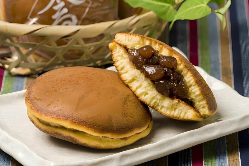 半分に割られた「高田屋のどら焼き」が皿に盛られた断面画像。和菓子職人の父子が手焼きしたしっとり生地と、北海道産大納言小豆の自家製粒餡がたっぷり詰まった様子。