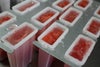 溶けないアイスキャンデーの生地を、アイスの型に流し込んでいる製造工程の画像。葛と果肉を混ぜた、もちシャリ食感を生み出す特別な工程。
