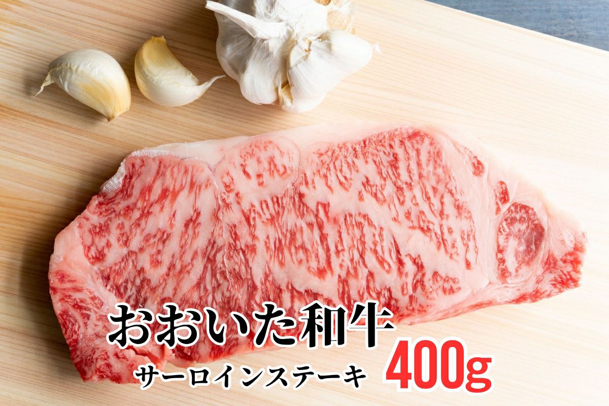 大分県のブランド牛「おおいた和牛（黒毛和牛）」のサーロインステーキ肉を、ニンニクと共にまな板に置いた調理前のイメージ画像。美しい霜降りと厚みのある高級ステーキ。
