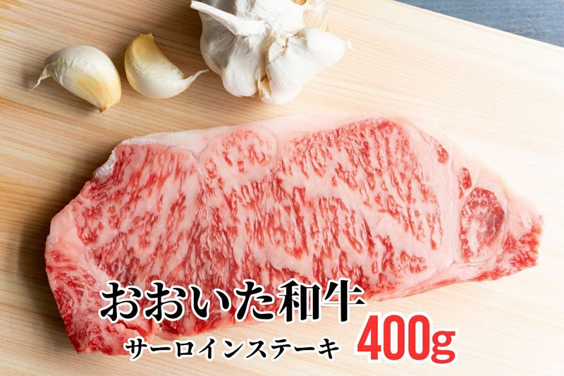 大分県のブランド牛「おおいた和牛（黒毛和牛）」のサーロインステーキ肉を、ニンニクと共にまな板に置いた調理前のイメージ画像。美しい霜降りと厚みのある高級ステーキ。