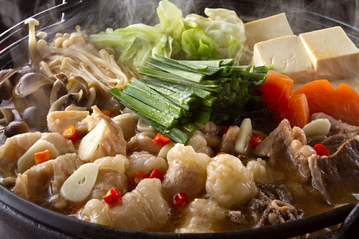 日田のホルモン専門店【福地のうなるホルモン】のもつ鍋セットを、野菜と共に鍋で煮込んでいる調理中の画像。特製スープとぷりぷりのもつの旨味が溶け合った本格的なもつ鍋。