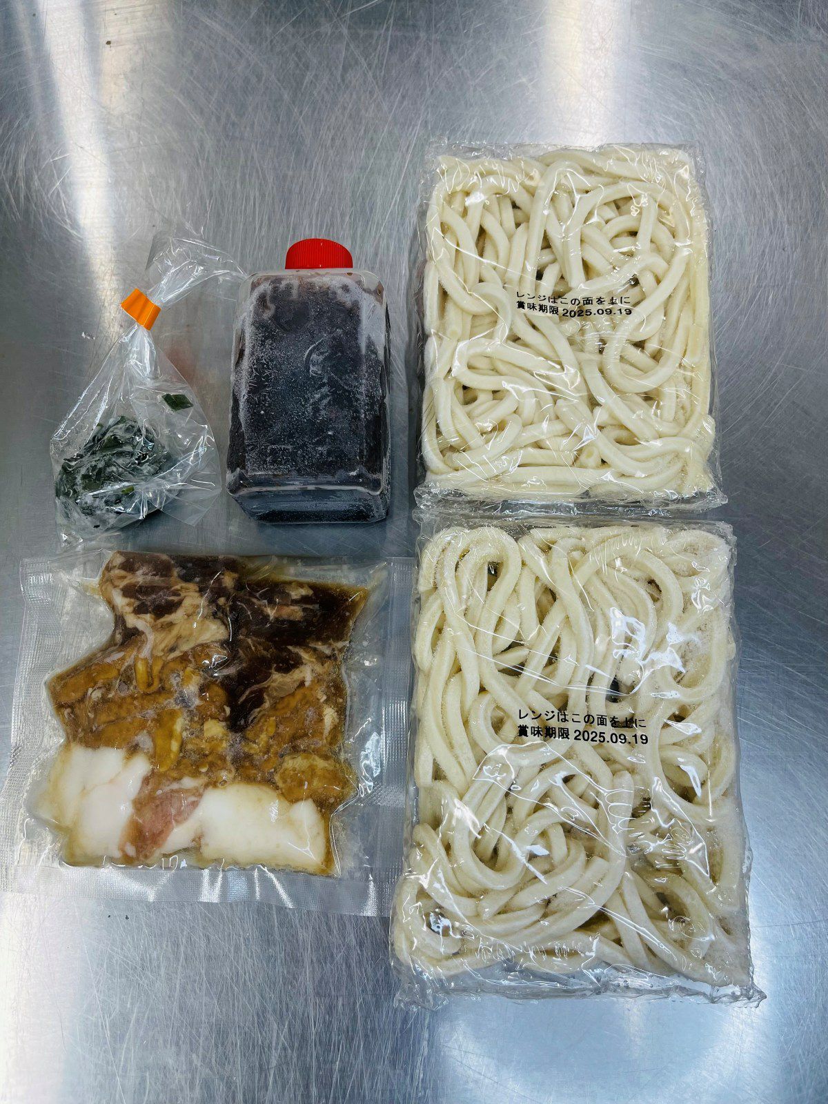 「焼きうどんセット（2人前）」のうどん麺、特製タレ、ホルモン、ネギを個別に並べた内容量画像。冷凍のお取り寄せセット。