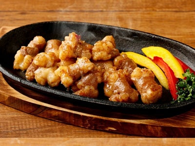 特製タレに漬け込んだ「牛丸腸」を鉄板で焼いている調理中の画像。牛脂が溶け出し、ジュージューと音を立てるぷりぷりの丸腸の様子が伝わる焼肉風景。