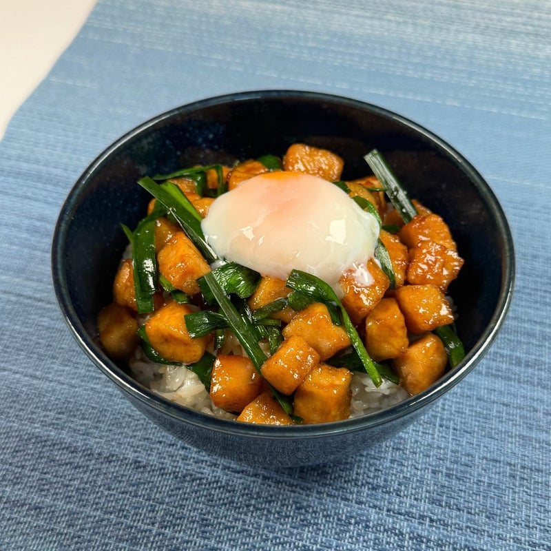 大分名物「トリニータ丼」に半熟卵をトッピングした画像。鶏肉とニラの旨味に、卵のまろやかさが加わり、濃厚な味わいを楽しめる調理例。