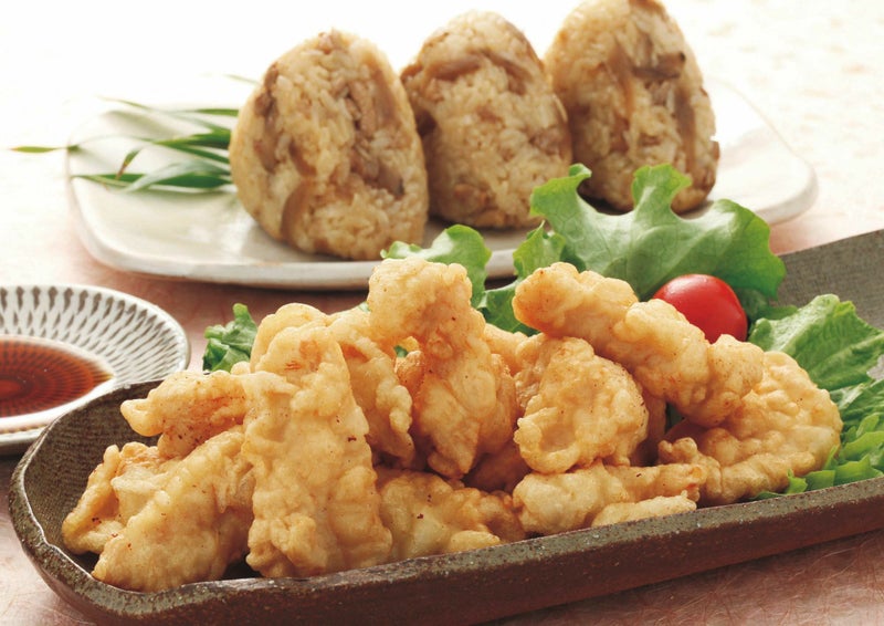 大分名物「とり天」と「鶏めしおにぎり」を食卓に並べた画像。大分の郷土料理を自宅で手軽に楽しめる、豪華な食卓の様子。