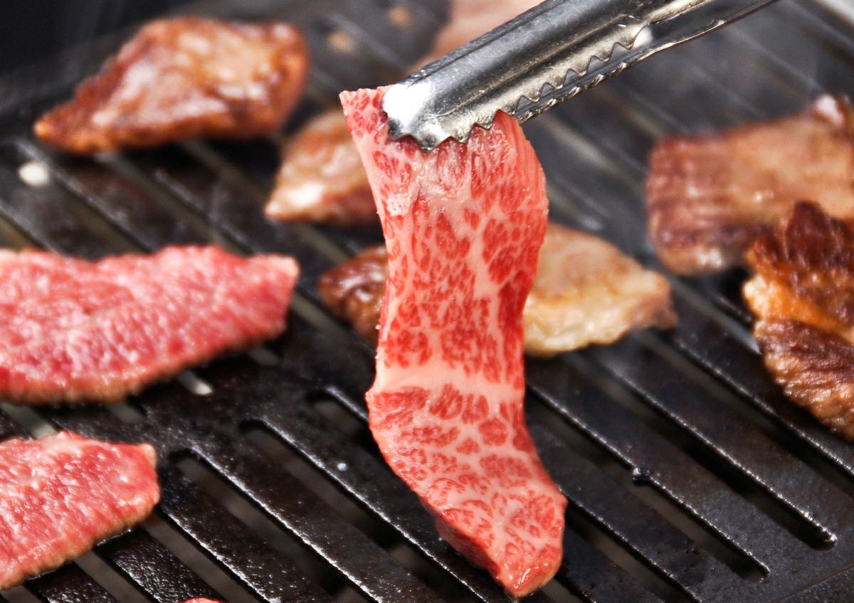 大分県産「おおいた和牛カルビ」を鉄板または網で焼いている調理中の画像。上質な脂が溶け出し、ジュージューと音を立てる、食欲をそそる焼肉風景。