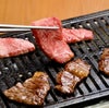 大分県のブランド牛「おおいた和牛」の霜降り肉を鉄板または網で焼いている調理中の画像。高級和牛の脂が溶け出し、食欲をそそる焼肉風景。