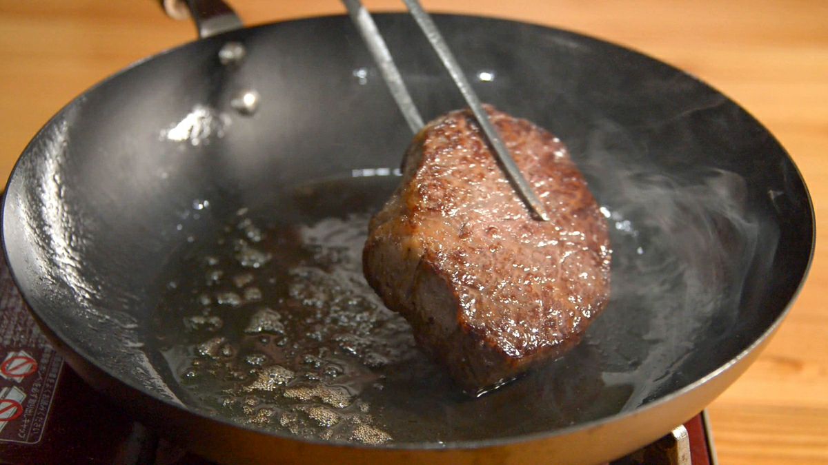 大分県産「おおいた和牛ヒレステーキ」を鍋に多めの油をひいて、表面をカリッと焼き上げている調理中の画像。高級ヒレ肉を自宅でプロの仕上がりにできる様子。