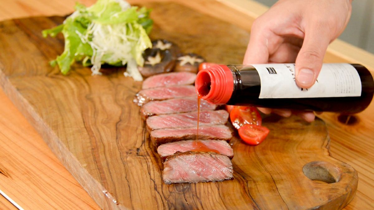 焼き上げた「おおいた和牛ヒレステーキ」を一口サイズにカットし、付属のステーキソースをかけている画像。肉の断面の美しさと、柔らかな食感が伝わる。