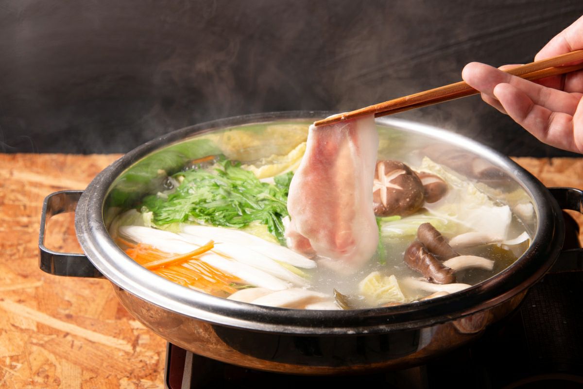 大分県のブランド豚「奥豊後豚」のしゃぶしゃぶ肉を鍋の湯にくぐらせている調理中のアップ画像。程よく火が通った豚肉の様子が伝わる。