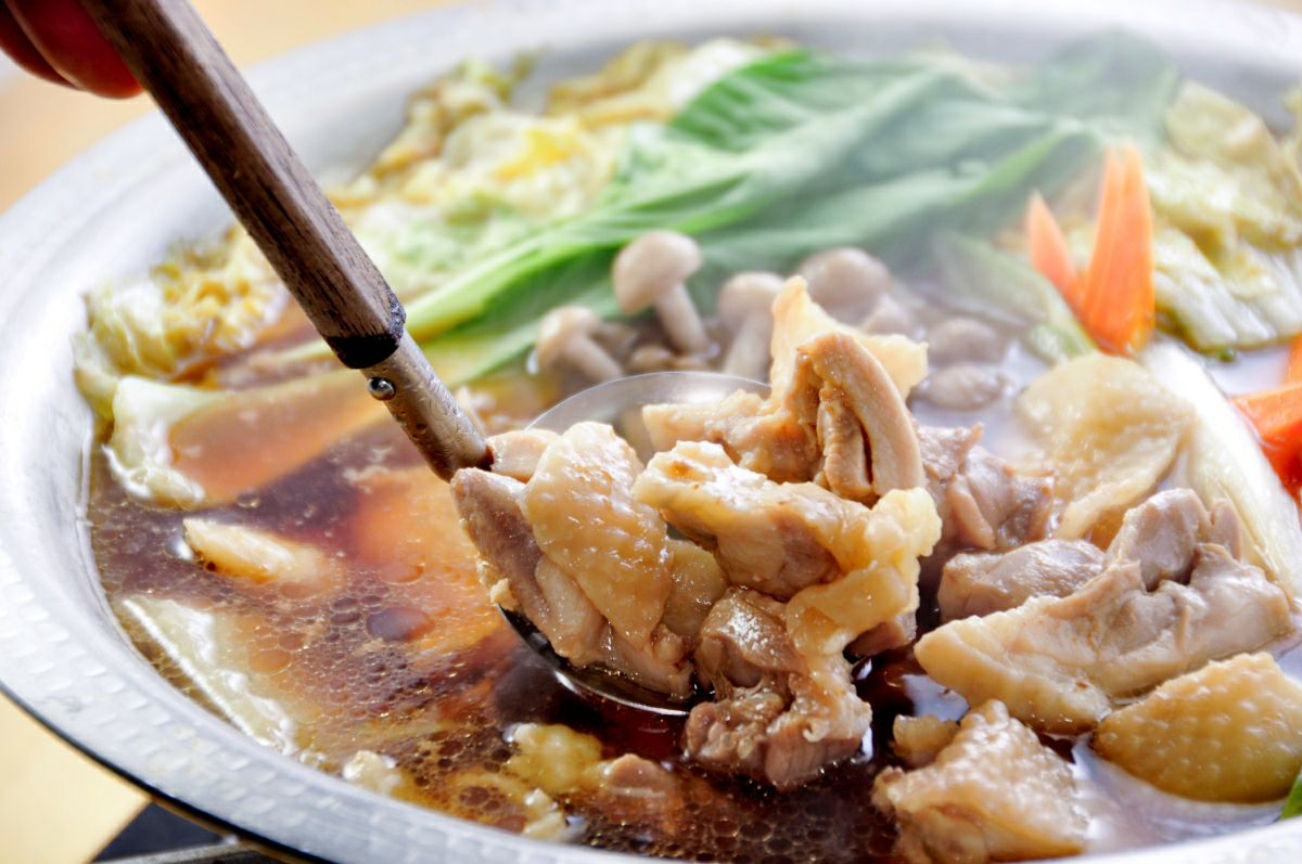 「おおいた冠地どり」の鶏肉を鍋で煮込んでいる調理中の画像。地鶏の豊かな出汁と旨味が溶け込み、鍋料理やすき焼きに最適な様子。