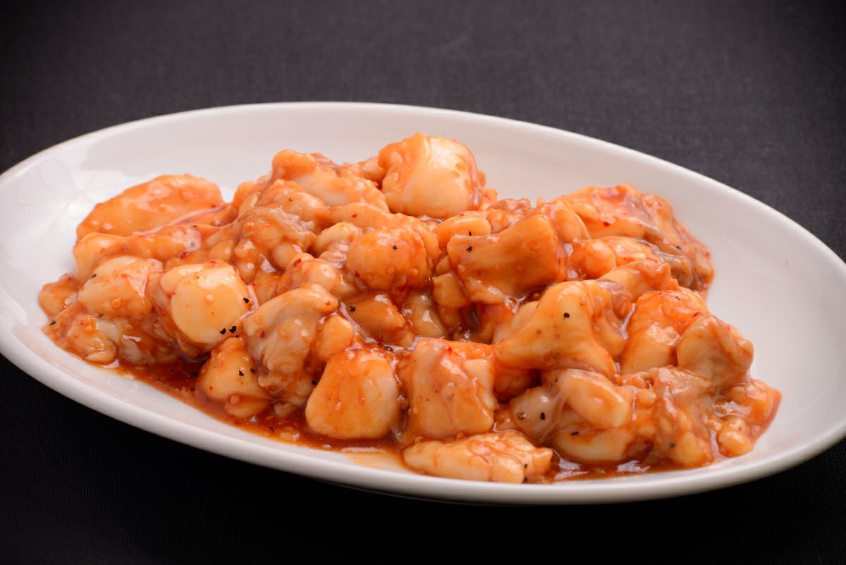 国産の新鮮なホルモンと野菜を皿に盛り付けた調理前の画像。焼肉やバーベキュー（BBQ）、もつ鍋に使える大容量1.2kgの国産ホルモンセット。