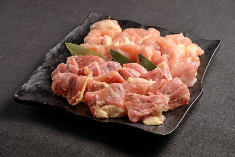 大分県のブランド鶏「おおいた冠地どり」の新鮮な鶏肉を皿に盛り付けた画像。豊かな風味と適度な歯ごたえが特徴の冠地どりを、様々な料理に活用できる1kgセット。