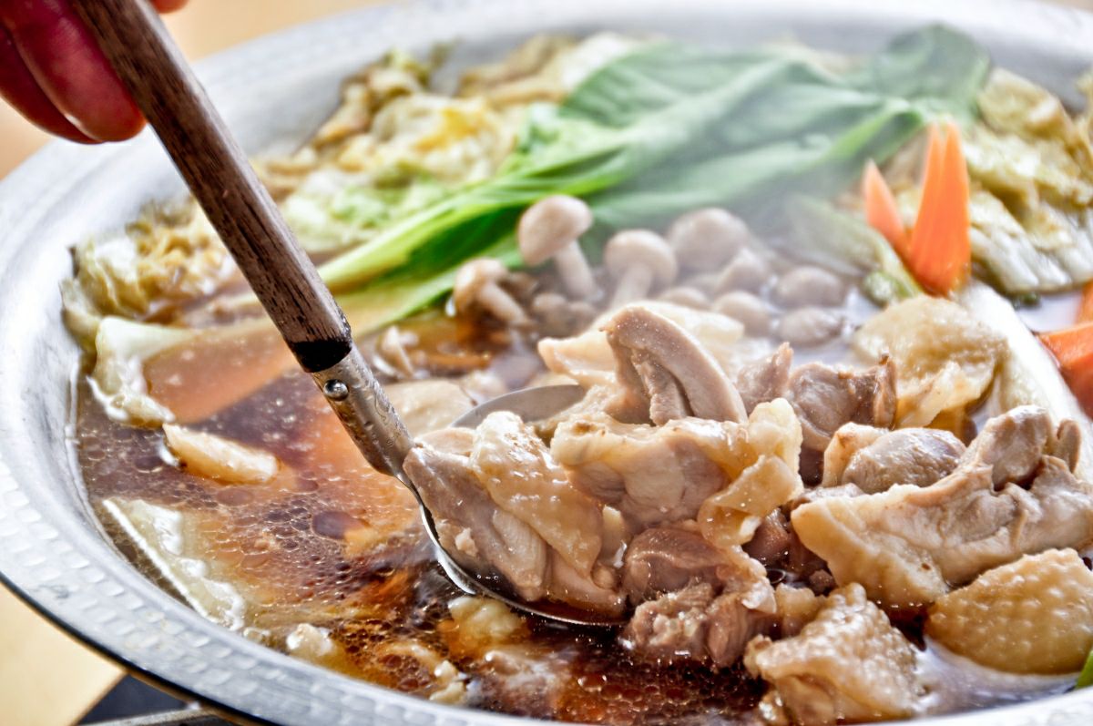 大分県産「おおいた冠地どり」の鶏肉を鍋で煮込んでいる調理中の画像。地鶏の豊かな出汁と旨味がスープに溶け込み、鍋料理や煮物に最適な様子。