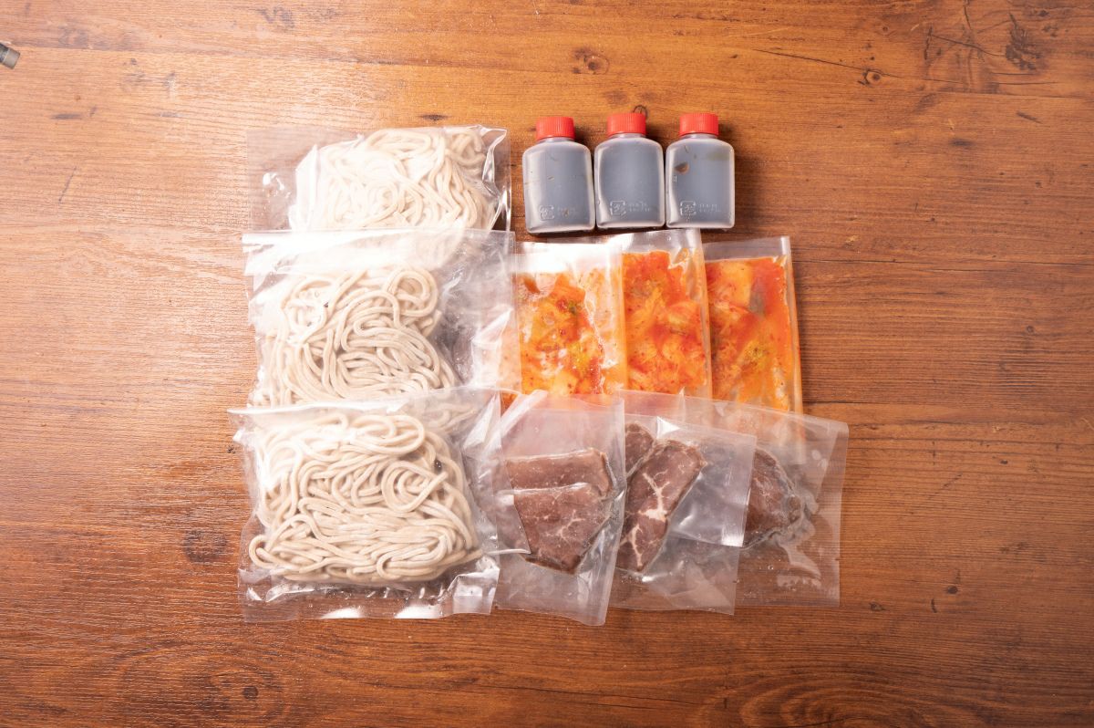 「別府冷麺」の麺、スープ、キムチ、チャーシューなどの具材が個別にパックに詰められた内容量画像。ご自宅で本格的な別府冷麺を楽しめるお取り寄せセット。