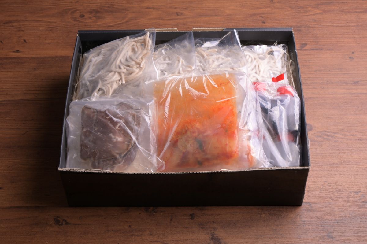 「別府冷麺」の麺、スープ、キムチ、チャーシューなどの具材が個別にパックに詰められた内容量画像。ご自宅で本格的な別府冷麺を楽しめるお取り寄せセット。