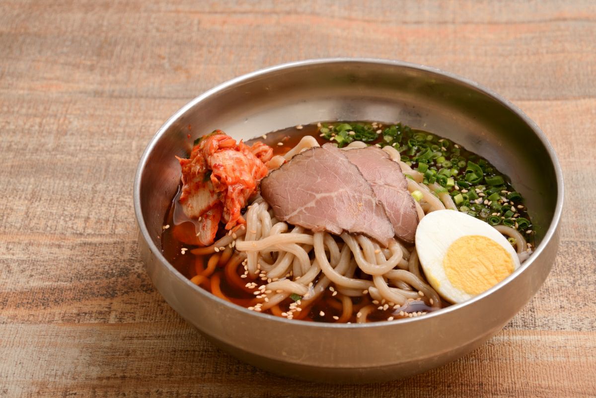 「別府温泉冷麺」の調理後の盛り付け画像。コシのある太麺と牛骨ベースの冷たいスープ、チャーシューやキムチなどが盛り付けられた、別府のご当地グルメ。