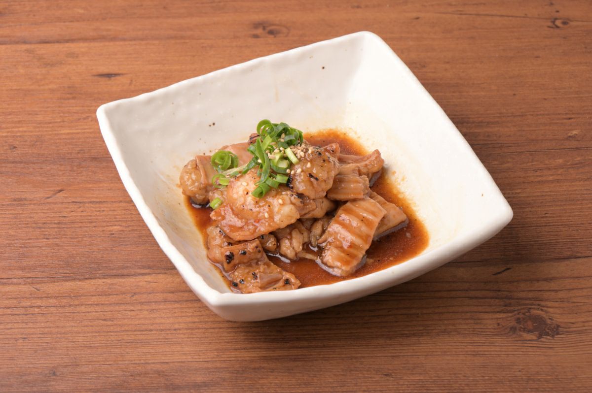 調理後の「元祖ホルモン丼の具」のホルモン部分を皿に盛り付けた画像。焼肉や炒め物、お酒のおつまみとしても楽しめる、濃厚なタレ漬けホルモン。