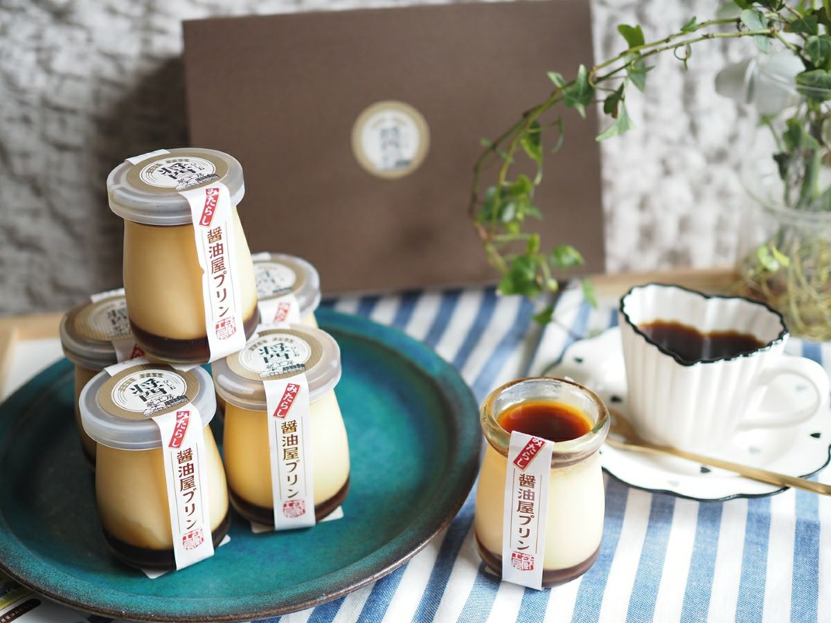 「みたらし醤油屋プリン」とコーヒーがテーブルに並んだ、カフェのような雰囲気の画像。ご褒美スイーツや、和と洋の最高の出会いを楽しめるデザートシーン。