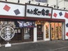 「太一商店」の実店舗外観の写真。行列のできる人気ラーメン店の雰囲気が伝わる、活気ある様子。
