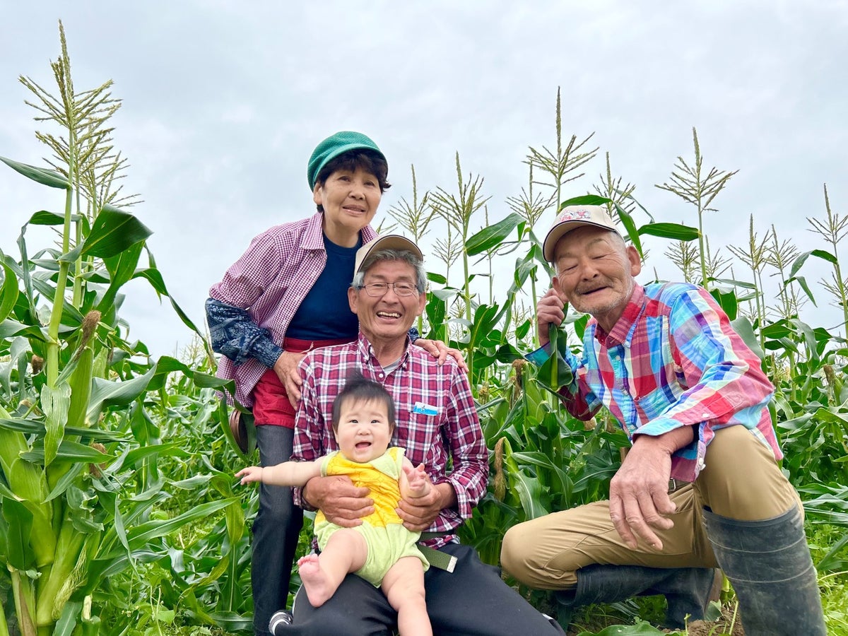 大分県竹田市のとうもろこし農家・卯野農場の皆さんと赤ちゃんの笑顔。安心・安全な野菜作りを象徴する家族写真